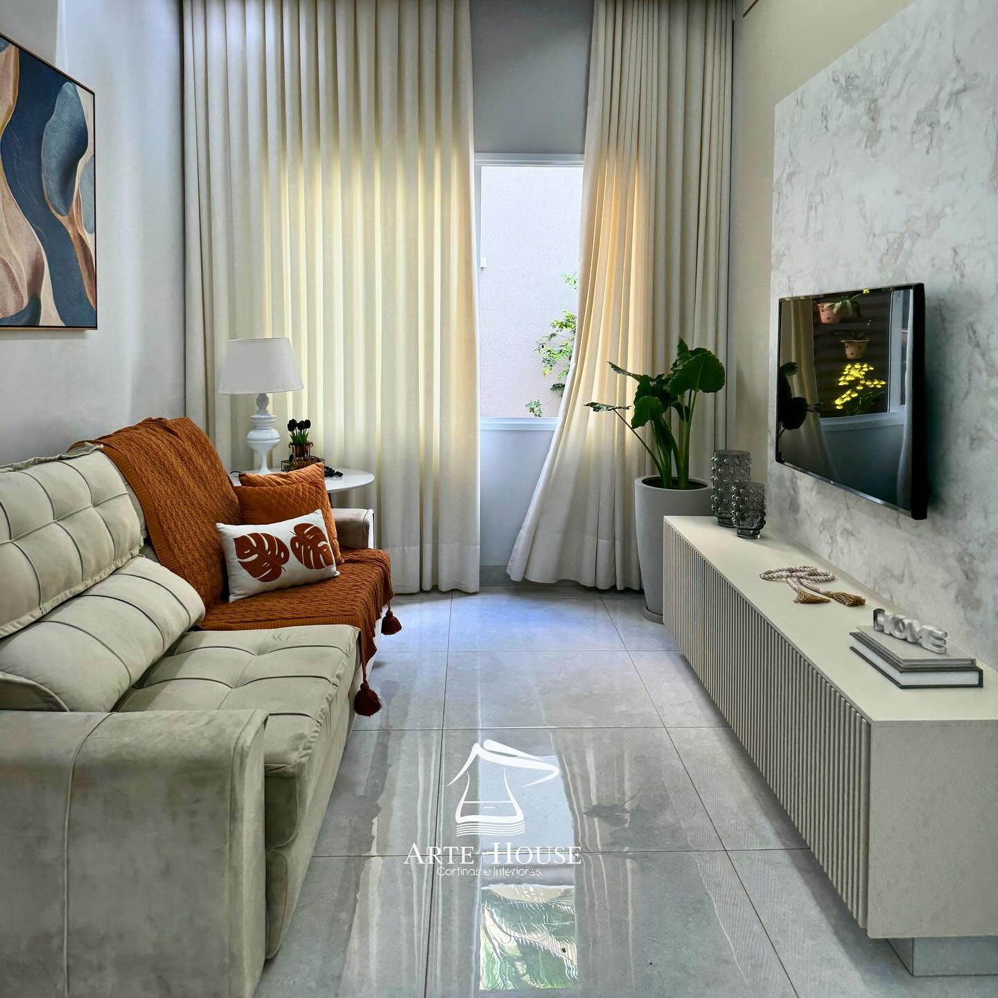 Sala de TV com cortina bege e detalhes em terracota