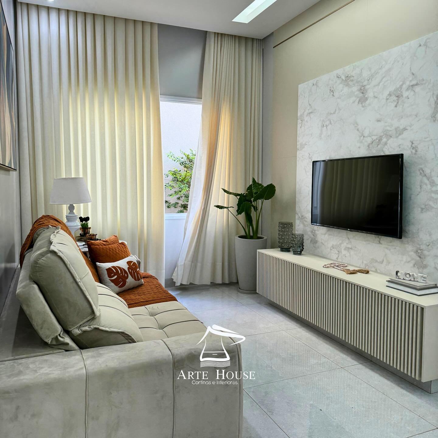 Cortina bege em sala de estar com painel de TV — projeto Arte House
